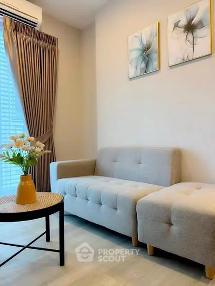 Cozy living room with modern sofa, stylish decor, and natural light from large window.