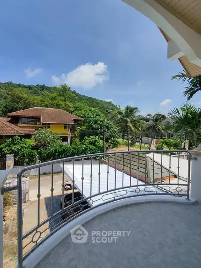 Charming balcony view with lush greenery and neighboring houses under a clear blue sky.