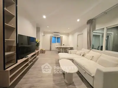 Spacious modern living room with elegant decor and large TV, perfect for relaxation and entertainment.