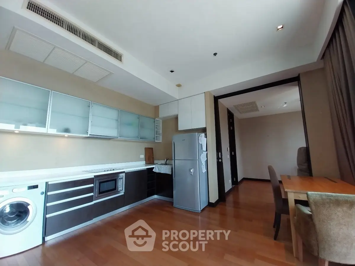 Modern kitchen with wooden flooring, sleek cabinets, and integrated appliances in open layout.