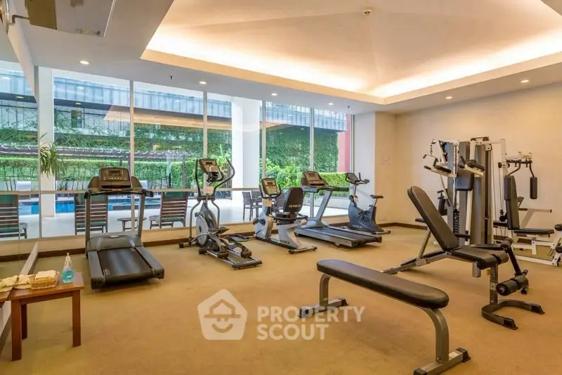 Modern gym with state-of-the-art equipment and pool view in luxury apartment complex.