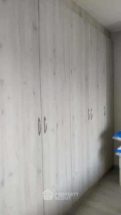 Spacious built-in wardrobe in modern bedroom with sleek wooden finish.