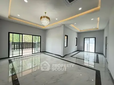 Spacious modern living room with elegant chandelier and large windows.