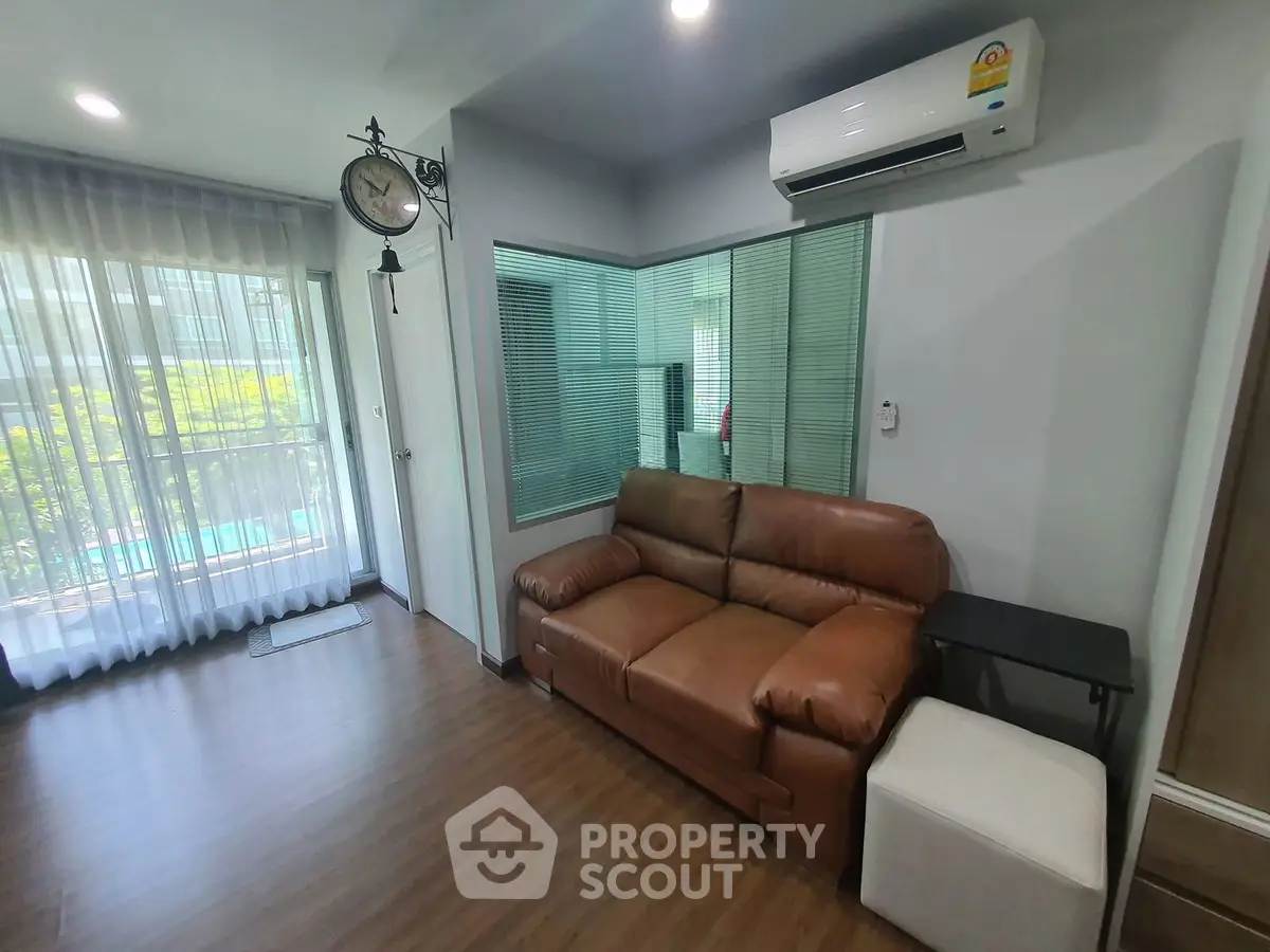 Modern living room with leather sofa and air conditioning, featuring large windows and stylish decor.