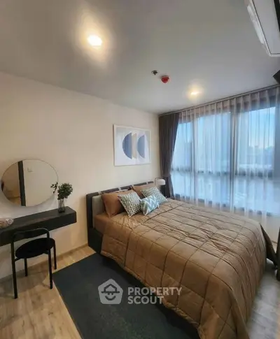 Modern bedroom with stylish decor and large window offering natural light.