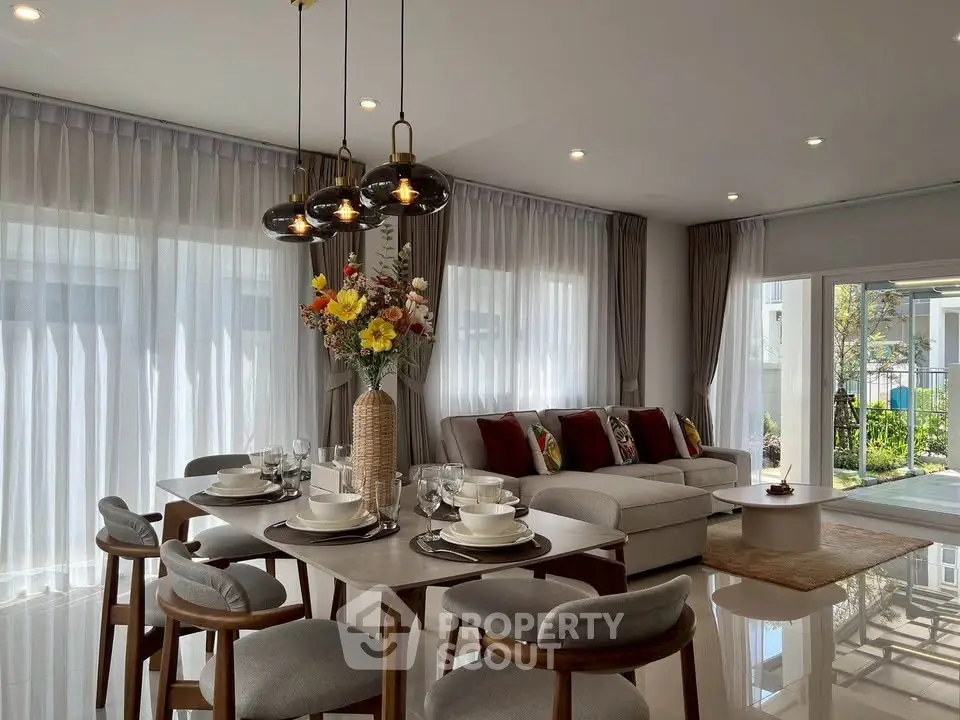 Elegant living room with modern dining area and cozy seating, featuring large windows and stylish decor.