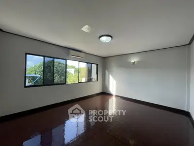 Spacious empty room with large windows and glossy wooden floor