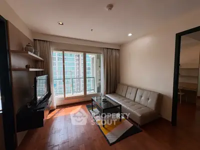 Modern living room with large window and city view, featuring sleek furniture and wooden flooring.