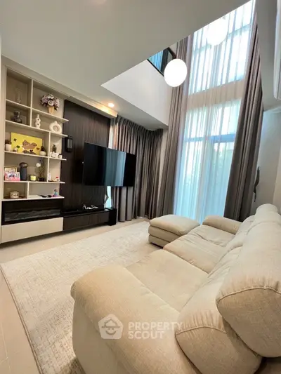 Luxurious living room with high ceilings and modern decor, featuring a plush sofa and elegant shelving unit.
