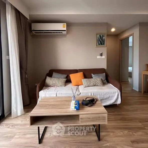 Modern living room with cozy sofa, air conditioning, and stylish wooden coffee table.