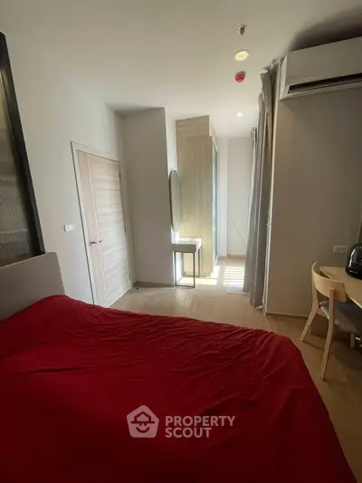 Cozy bedroom with red bedding, modern furniture, and natural light