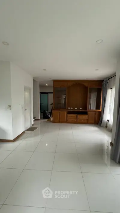Spacious living room with built-in wooden cabinet and large windows