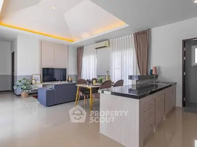 Modern open-plan living room with sleek kitchen and dining area, featuring elegant decor and ample natural light.