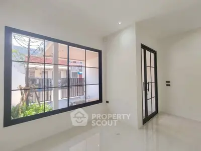 Bright modern room with large window and glass door, showcasing sleek design and natural light.