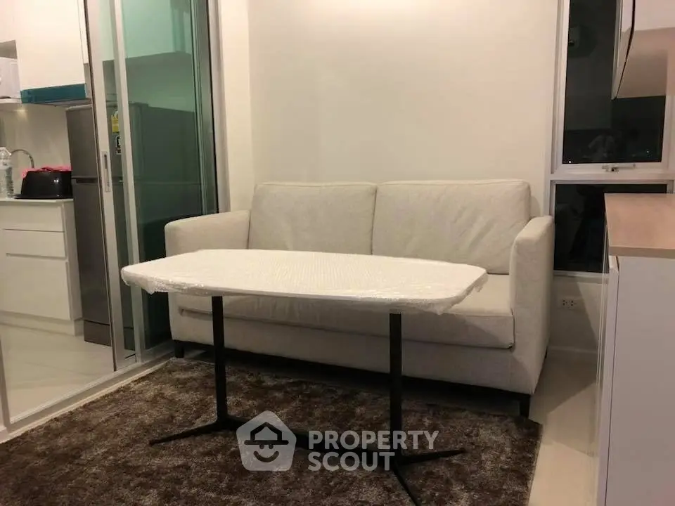 Modern living room with cozy sofa and sleek kitchen area in open layout apartment.