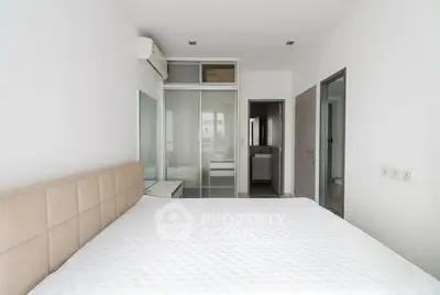 Modern minimalist bedroom with white walls and sliding glass closet doors.