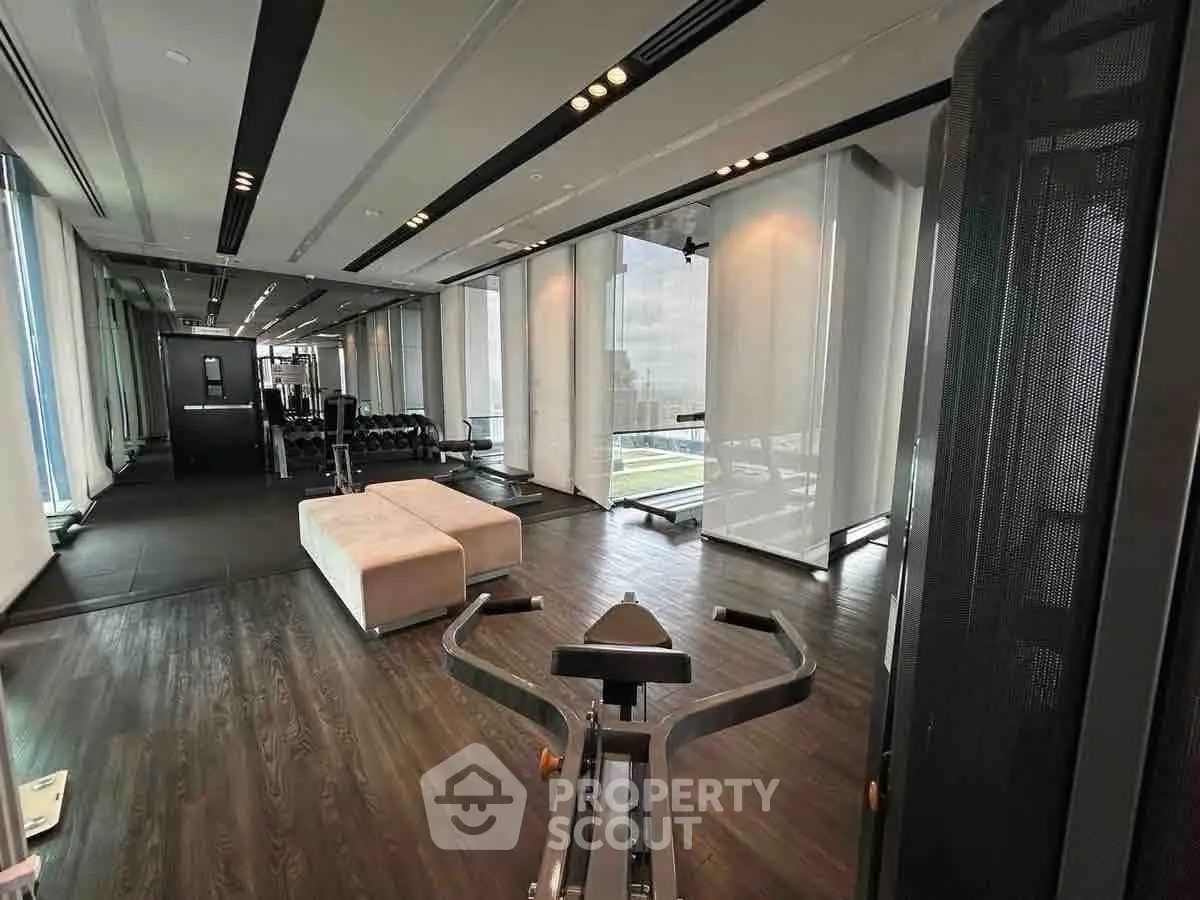 Luxurious gym with modern equipment and floor-to-ceiling windows offering stunning city views.