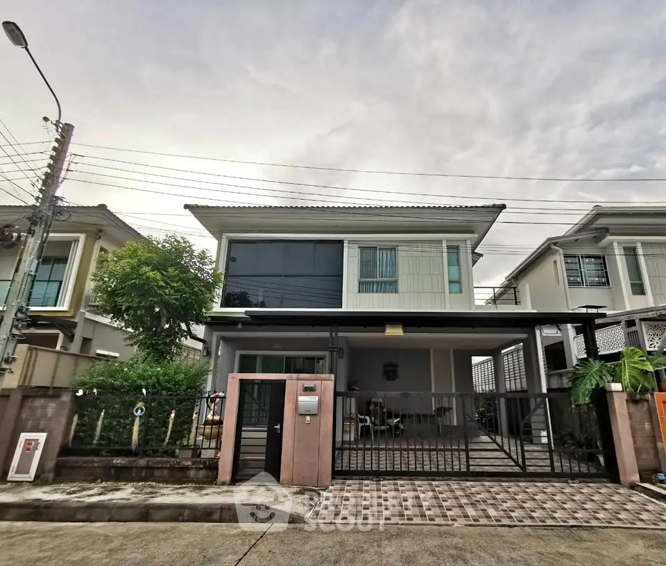 Modern two-story house with gated driveway and contemporary design in a suburban neighborhood.
