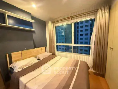 Cozy bedroom with large window and modern decor in urban apartment.