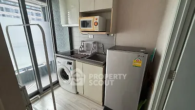 Compact kitchen with washing machine and microwave in modern apartment
