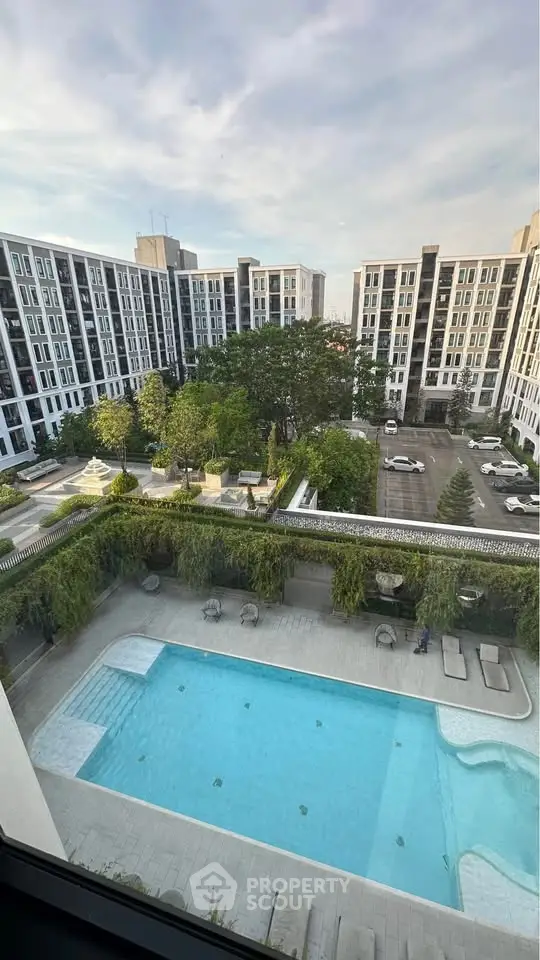Stunning view of modern apartment complex with pool and lush greenery.