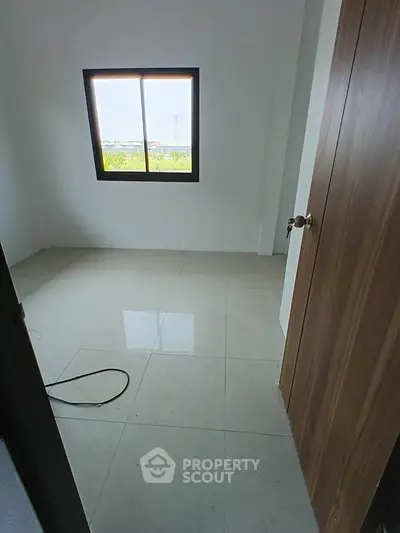 Bright empty room with large window and tiled floor, perfect for customization.