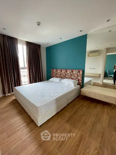 Spacious bedroom with modern decor and large window offering natural light.