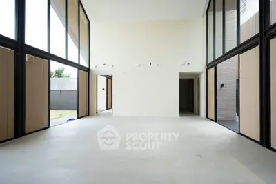 Spacious modern living room with high ceilings and large windows, offering abundant natural light and a minimalist design.