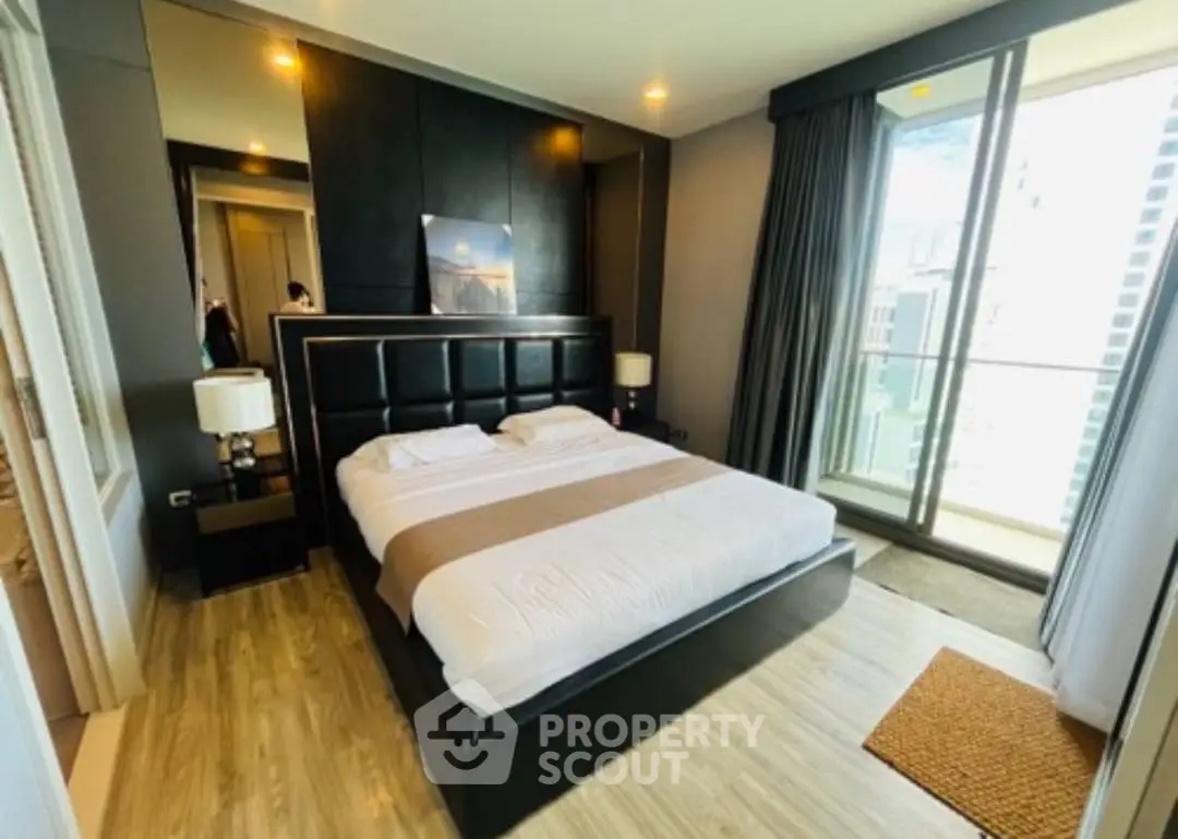 Luxurious bedroom with modern decor and balcony view in upscale apartment.
