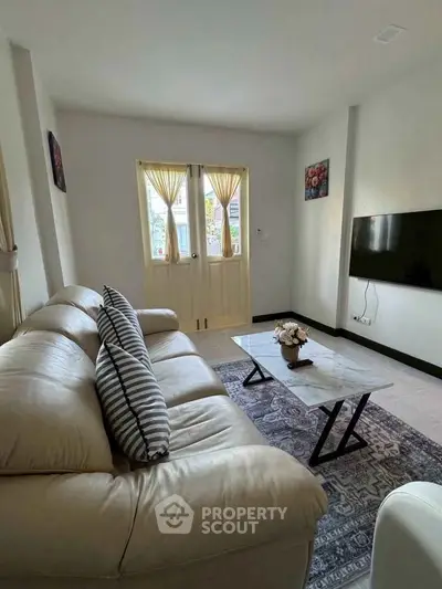 Charming living room with cozy sofa and wall-mounted TV, perfect for relaxation.