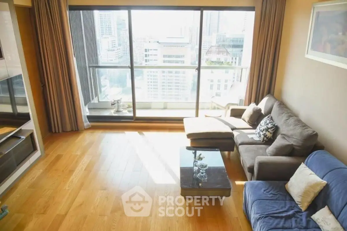 Spacious living room with large windows offering stunning city views and cozy seating area.