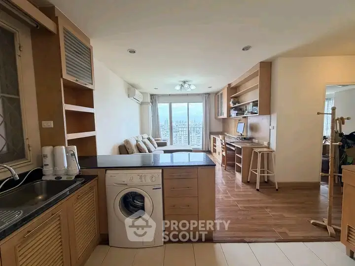 Spacious open-plan living room with kitchen and city view, featuring modern appliances and cozy seating area.
