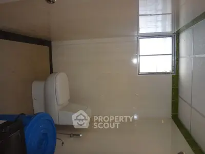 Simple bathroom with toilet and window, featuring basic tiling and minimal decor.