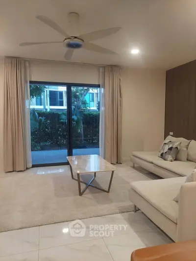 Spacious living room with modern decor and large sliding glass doors leading to a lush garden view.