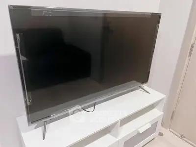 Modern living room with sleek TV on stylish white stand, perfect for entertainment setup.
