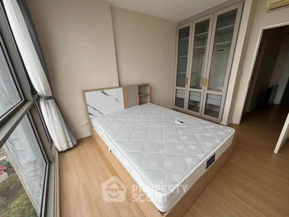 Spacious bedroom with large windows and built-in wardrobe, offering ample natural light and storage.