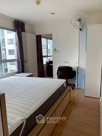 Bright bedroom with modern furniture and large windows in urban apartment.