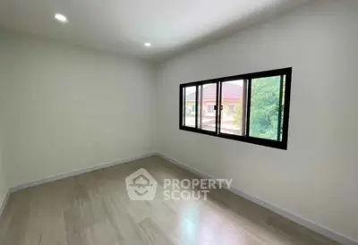 Spacious empty room with large window and wooden flooring, ideal for customization.