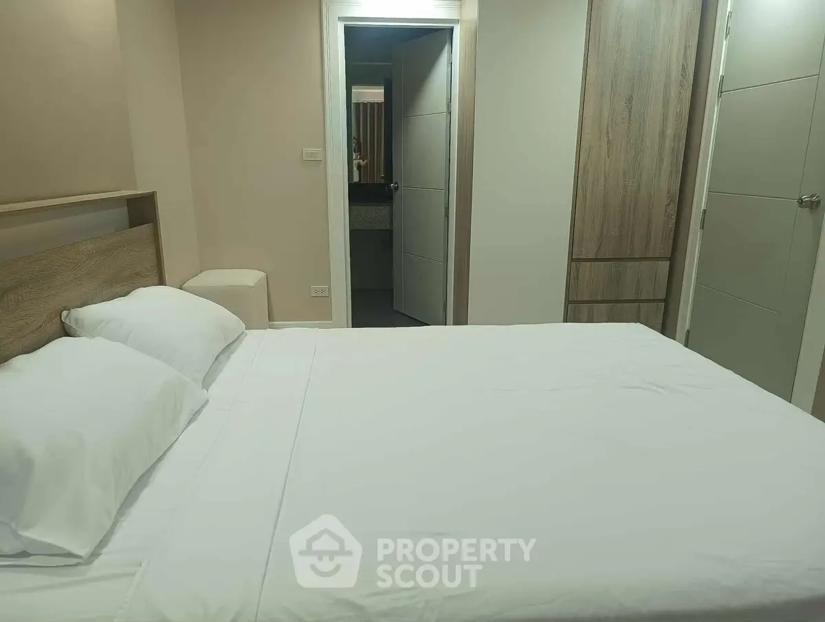 Cozy bedroom with modern furnishings and a glimpse into the ensuite bathroom.