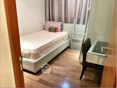 Cozy bedroom with wooden flooring and modern furnishings in a stylish apartment.