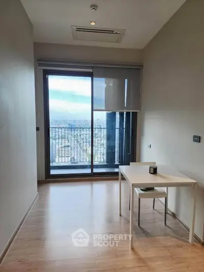 Modern minimalist room with large window and city view, featuring sleek wooden flooring and a simple white table.