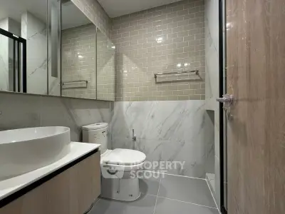 Modern bathroom with sleek design, featuring a large mirror, stylish sink, and elegant tile work.