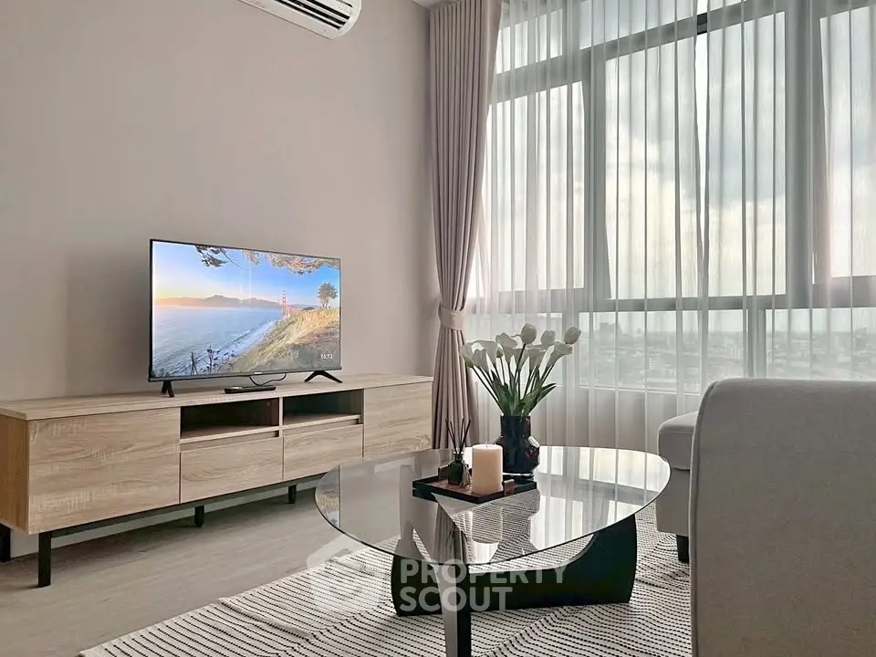 Modern living room with large window, stylish furniture, and scenic view on TV screen.