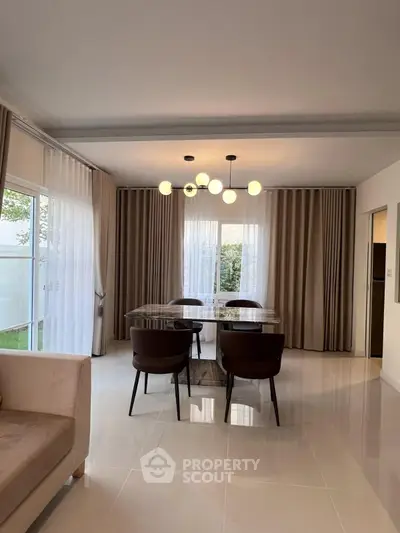 Elegant dining area with modern chandelier and large windows in a stylish home.