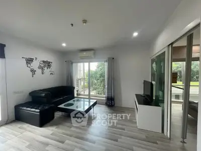 Modern living room with sleek black sofa and glass coffee table, featuring a balcony view.