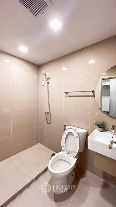 Modern bathroom with sleek tiles, shower, and compact fixtures in a contemporary apartment.