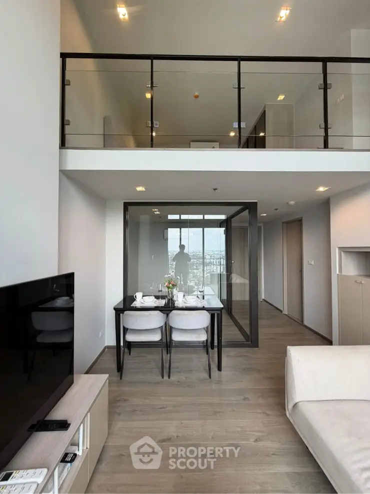 Modern duplex apartment with open living area and glass balcony, featuring sleek dining setup and expansive city views.