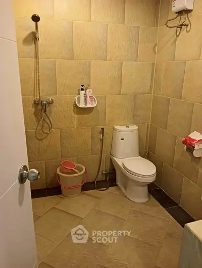 Modern bathroom with tiled walls and essential fixtures, featuring a shower and toilet.