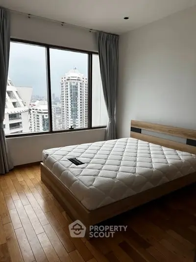Spacious bedroom with large window offering stunning city views in modern apartment.