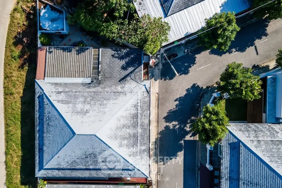 Aerial view of residential neighborhood with rooftops and street.